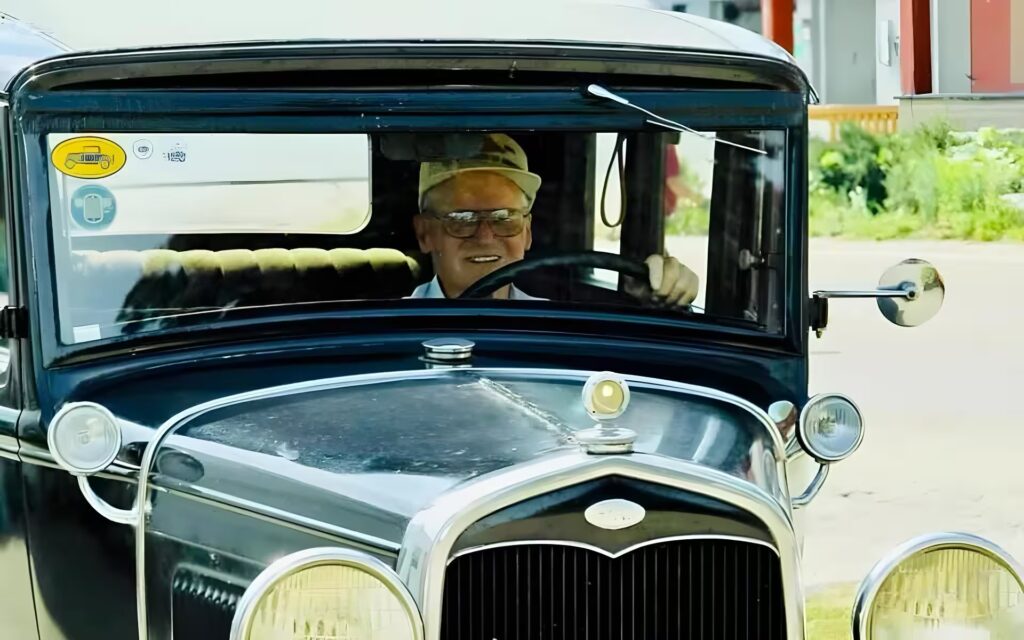 An old man driving a vintage car